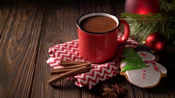 Zelfgemaakte warme chocolademelk in rode mok met kaneel en peperkoek op houten ondergrond — Stockvideo
