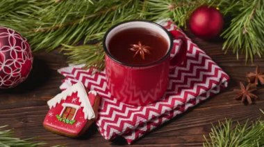 Kırmızı bardak meyve çayı ve Noel süslemeleri köknar ağacı dallarıyla ahşap masada.
