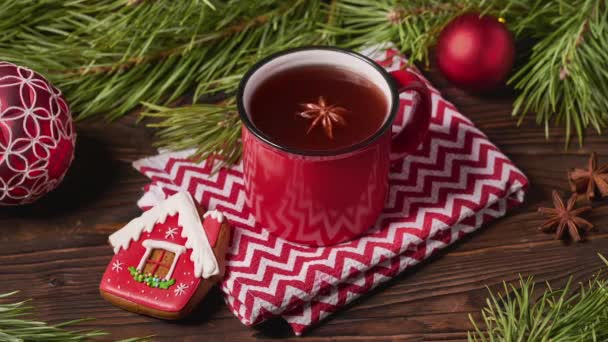 Taza roja de té de frutas y decoraciones navideñas en mesa de madera con ramas de abeto — Vídeos de Stock