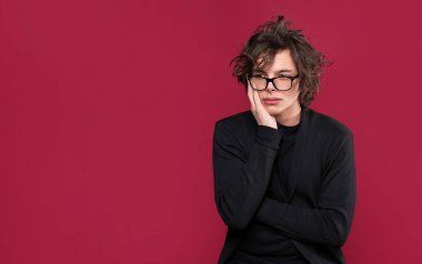 Düşünceli ve üzgün bir ifadeyle yan bakan beyaz bir genç.