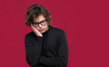 Düşünceli ve üzgün bir ifadeyle yan bakan beyaz bir genç.