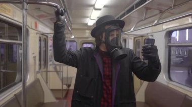 Gaz maskesi takan ve Coronavirus covid-19 'a karşı siyah tıbbi eldiven takan genç, siyah şapkalı yeniyetme çocuk metroda virüs, salgın ve salgın hastalıklardan korunuyor.