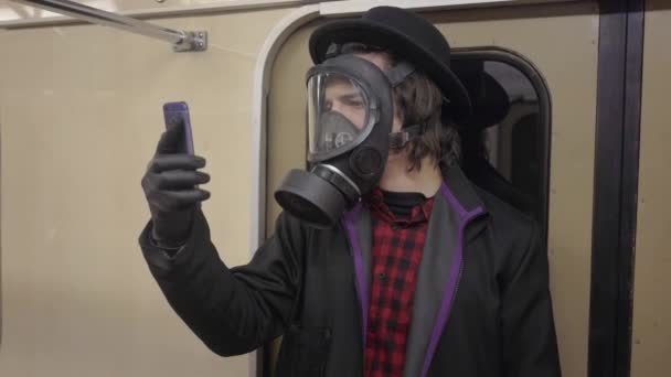 ガスマスクを身に着けている若い男とコロナウイルスに対する黒い医療手袋covid-19 、地下鉄でのウイルス、パンデミックや病気の流行の感染から保護する黒い帽子の千年のヒップスター少年 — ストック動画