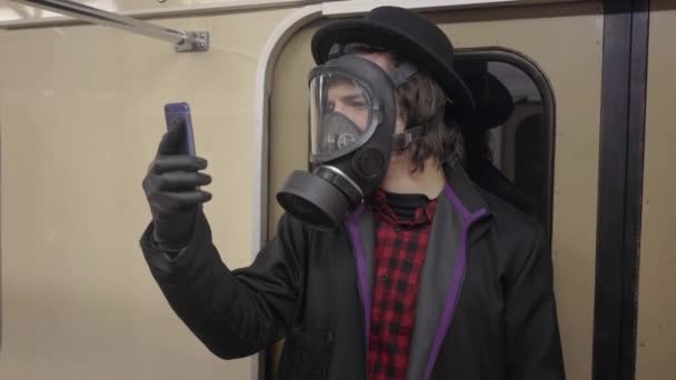 Giovane uomo con maschera antigas e guanti medici neri contro il coronavirus covid-19, ragazzo hipster millenial in cappello nero che protegge dall'infezione da virus, pandemia ed epidemia di malattia in metropolitana — Video Stock