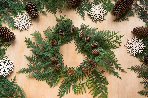 Preparation for Christmas holiday. Christmas composition of wreath, decor, dry orange, twigs and snowflakes. Woman prepare a wreath. Top view and copy space. Flat lay.