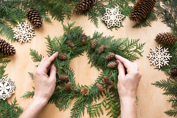 Preparation for Christmas holiday. Christmas composition of wreath, decor, dry orange, twigs and snowflakes. Woman prepare a wreath. Top view and copy space. Flat lay.