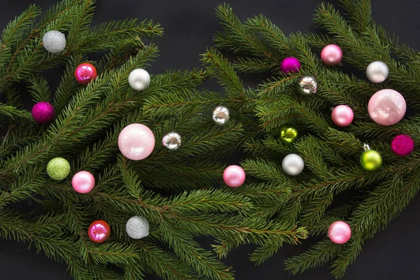 Christmas or New Year decoration background: fir-tree branches, colorful glass balls on black background with copy space. Top view. — Stock Photo, Image