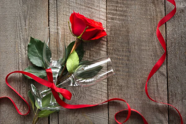 Tarjeta de San Valentín. Rosa roja y dos copas de vino sobre tabla de madera. Vista superior . — Foto de Stock