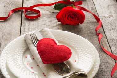 Romantik bir akşam yemeği kavramı. Ahşap arka plan üzerinde Sevgililer günü Festival Tablo ayarı. Kırmızı kurdele ile masaya gül..