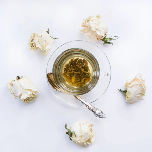 Cup of green tea with dry white roses around. Square. Isolated. Toned. — Stock Photo, Image