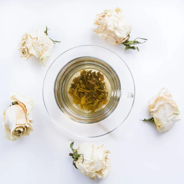 Cup of green tea with dry white roses around. Toned. — Stock Photo, Image