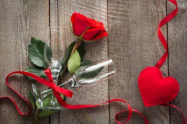 Sevgililer günü kartı. Kırmızı gül ve ahşap tahta üzerinde iki bardağı. Üstten Görünüm.