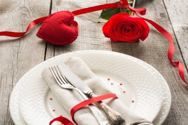 Romantik bir akşam yemeği kavramı. Ahşap arka plan üzerinde Sevgililer günü Festival Tablo ayarı. Kırmızı kurdele ile masaya gül..