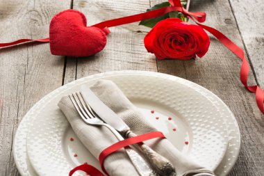 Romantik bir akşam yemeği kavramı. Ahşap arka plan üzerinde Sevgililer günü Festival Tablo ayarı. Kırmızı kurdele ile masaya gül..
