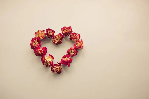Tarjeta de San Valentín. Símbolo del corazón hecho de rosas secas sobre un fondo vintage. Vista superior, cama plana. Concepto, postal con lugar para su texto. Filtro Vintage . — Foto de Stock