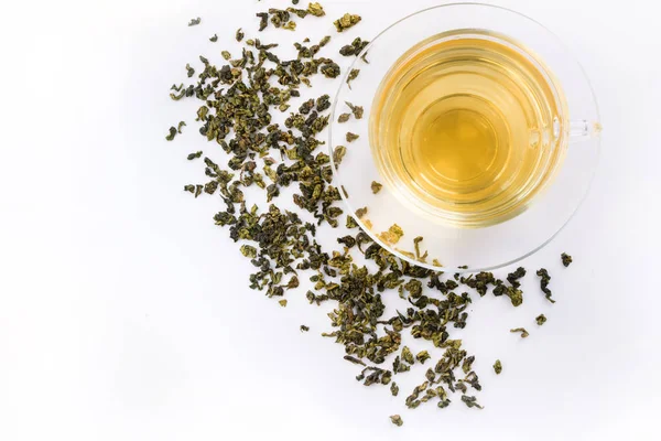 Üveg csésze zöld tea és száraz levelek a zöld tea, fehér háttér. — Stock Fotó