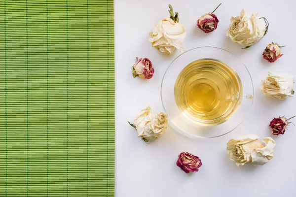 Üveg csésze zöld tea, száraz Fehér Rózsa körül. Elszigetelt. Tónusú. — Stock Fotó