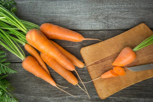 Zanahorias orgánicas frescas con tapas verdes en la mesa de madera, primer plano. Vista superior. Cocinar . — Foto de Stock