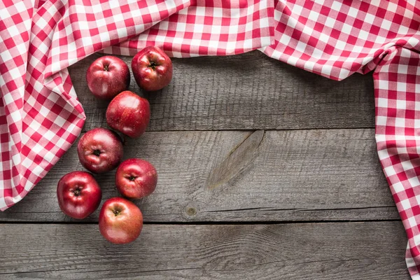 Manzanas rojas maduras en tablero de madera con servilleta a cuadros roja alrededor y espacio de copia . — Foto de Stock