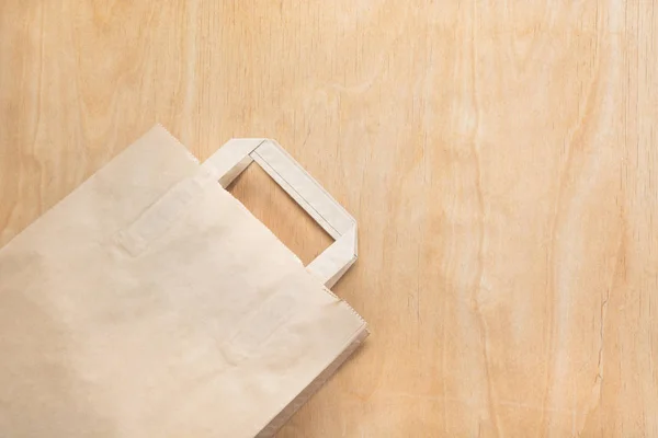 Bolsa de papel kraft marrón limpio acostado en una mesa de madera contrachapada . — Foto de Stock