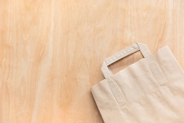 Bolsa de papel kraft marrón limpio acostado en una mesa de madera contrachapada . — Foto de Stock