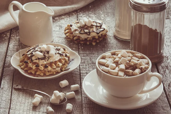 Weiße Tasse Kaffee mit Milch, Eibisch und hausgemachte Waffel mit Schlagsahne mit Dekor darüber. Leckeres Frühstück. Jahrgang abgemildert. — Stockfoto