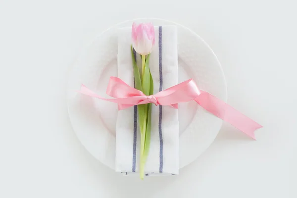 Eleganz Tischdekoration mit rosa Band und Tulpe auf weißem Hintergrund. Frühlingsromantisches Abendessen. Ansicht von oben. — Stockfoto