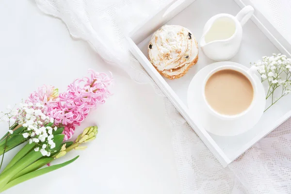 Café da manhã na primavera com uma xícara de café preto com leite e doces nas cores pastel, um buquê de jacinto rosa fresco em um fundo branco. Vista superior . — Fotografia de Stock