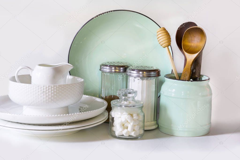 Crockery, tableware, utensils and other different white and turquoise stuff on white table-top. Kitchen still life as background for design.  Image with copy space.