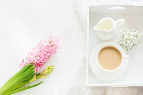 Morning breakfast in spring with a cup of black coffee with milk in the pastel colors, a bouquet of fresh pink hyacinth on a white background. Top view and copy space. — Stock Photo, Image