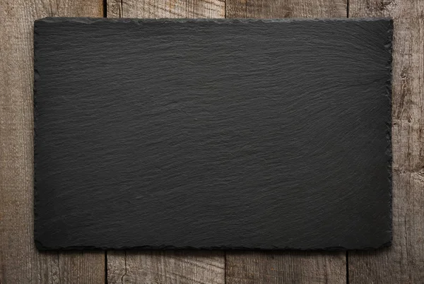 Black slate tile on wooden background . — Stock Photo, Image