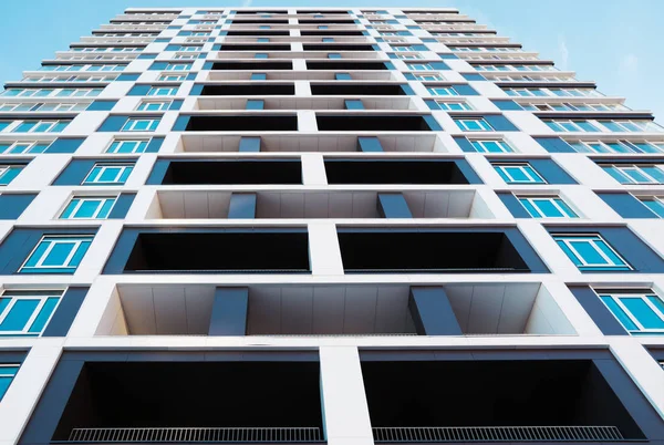 Modern and new apartment building. Photo of a tall block of flats with balconies against a blue sky.
