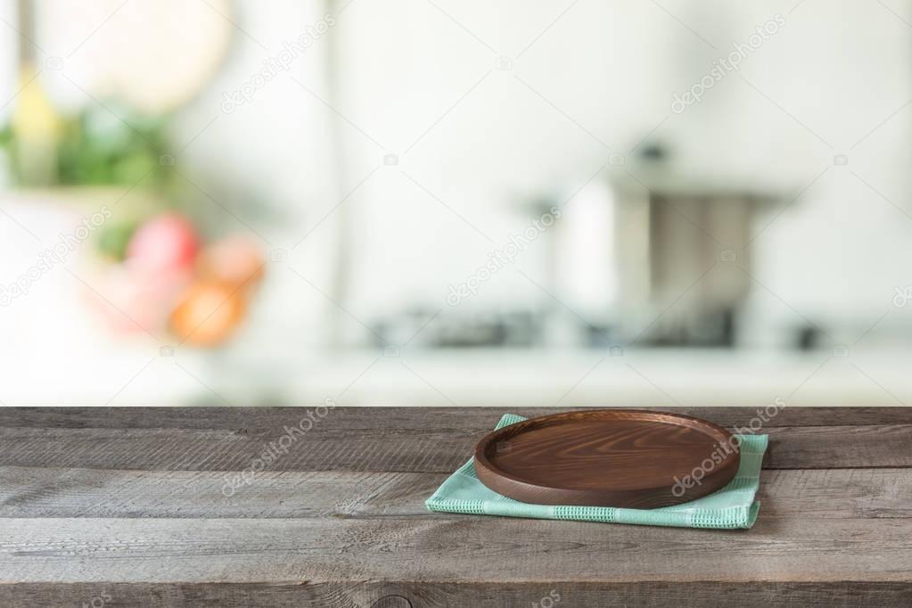 Blurred and abstract background. Empty wooden tabletop with tray and defocused modern kitchen background for display or montage your products.