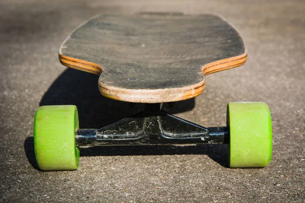 Old used longboard on the ground. Old style. Black skateboard on an empty asphalt road. Shallow depth of field. Close up. — Stock Photo, Image