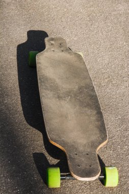 Eski longboard asfaltta kullanılan. Eski stil. Siyah kaykay bir boş asfalt yol üzerinde. Dikey.