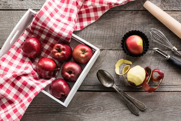 Зрізати червоні яблука в березовому лотку на дерев'яній дошці з червоною картатою серветкою, аксесуарами для випічки та копіювання місця для тексту . — стокове фото