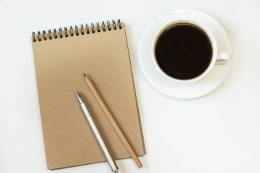 Kraft kağıt, kalem, bardak kahve beyaz zemin üzerine defter ile çalışma alanı. Metniniz için kopya alanı ile görüntü.