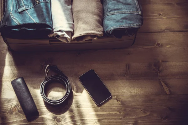 Maleta abierta con ropa masculina para viajar por el suelo de madera. Imagen tonificada . — Foto de Stock