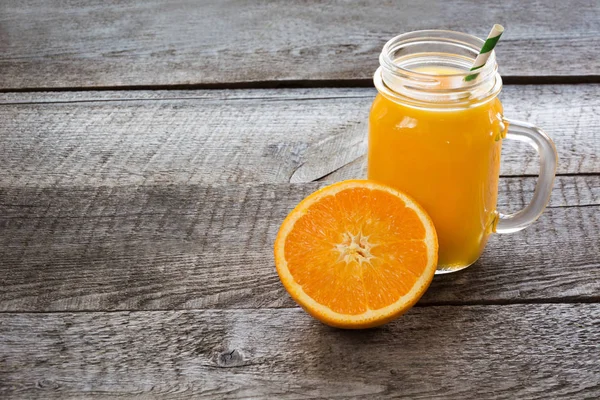 Batido de naranja en un frasco de vidrio de albañil con rebanada de naranja en el fondo de madera viejo . —  Fotos de Stock