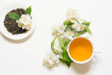 Beyaz arka plan üzerinde taze Yasemin çiçekleri ve çay ile Yasemin kuru yeşil çay yaprakları.