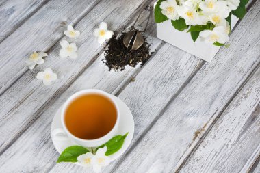Yasemin kuru yeşil çay taze Yasemin çiçekleri ve beyaz fincan yeşil çay ile ahşap arka plan üzerinde bırakır. Üstten Görünüm.