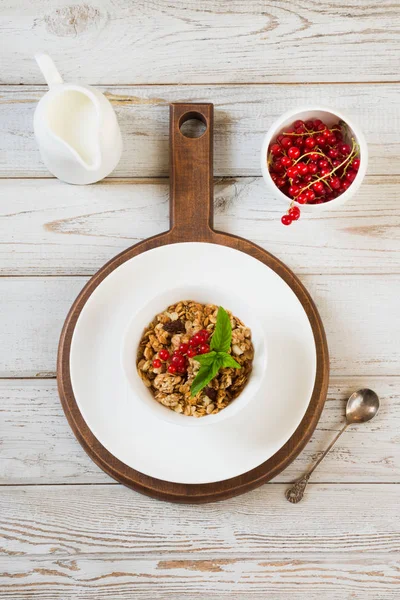 Desayuno saludable de verano de granola, muesli con jarra de leche con decoración de grosella roja en tablero de madera clara . — Foto de Stock