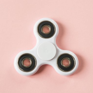 Beyaz parmak spinner stres, anksiyete Rölyef oyuncak kıpır. Pembe üzerinde düz lay.