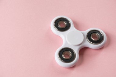 Beyaz parmak spinner stres, anksiyete Rölyef oyuncak kıpır. Pembe üzerinde düz lay.