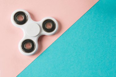 Beyaz parmak spinner stres, anksiyete Rölyef oyuncak kıpır. Düz mavi ve pembe üzerinde yatıyordu.