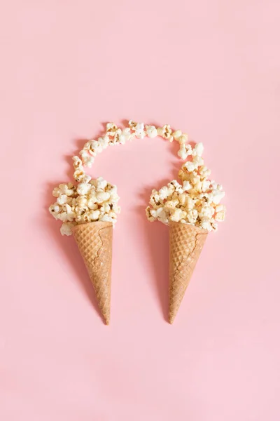 Popcorn v zmrzlinové kornouty na růžovém pozadí. Pohled shora. — Stock fotografie