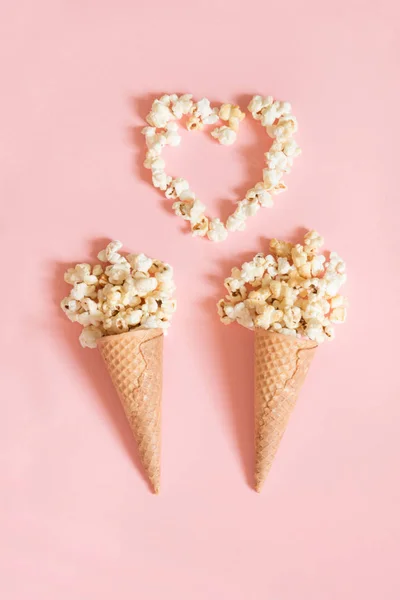 Popcorn v zmrzlinové kornouty na růžovém pozadí. Pohled shora. — Stock fotografie