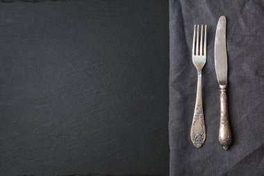 Rustik gri kumaş peçete, gümüş ve siyah arduvaz çanak ile kopya alanı menü veya tarifi için. Menü kartı restoranlar için. Üstten Görünüm.
