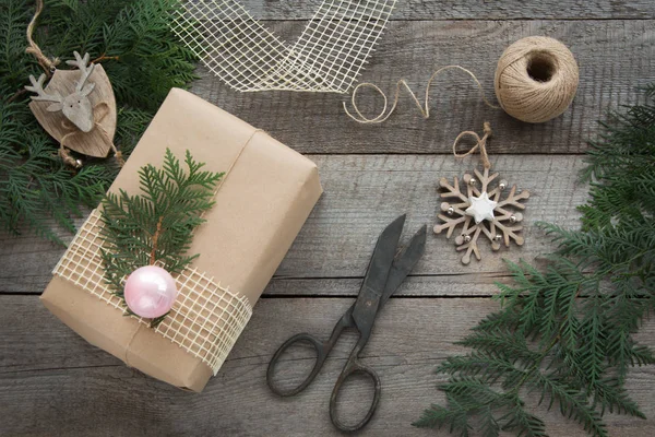 Preparation for Christmas holiday. Christmas Still life of  giftbox, decor, twine, fir tree, twigs, vintage scissors. Top view and copyspace. Flat lay.