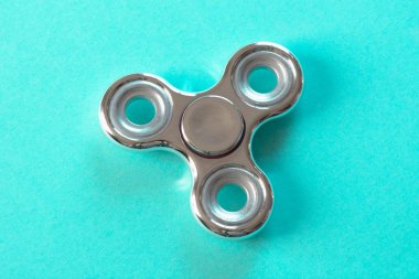 Topluca gümüş parmak parlak spinner stres. Düz mavi üzerinde yatıyordu.